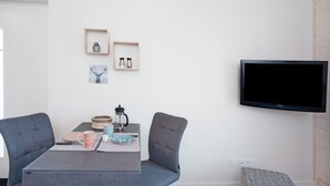 Una sala de estar moderna con una mesa de comedor, dos sillas, un televisor y adornos en la pared.