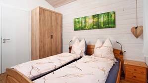 Un dormitorio con cama, armario, mesita de noche y un cuadro en la pared.
