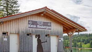 Un edificio de madera con un letrero que dice 'Kiosk Illasbergsee'.