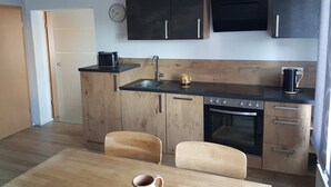 A compact kitchen with wooden cabinets, a built-in oven, a microwave, and a sink. - Apartment 'Ruth' with Private Terrace and Wi-Fi (Dahn)