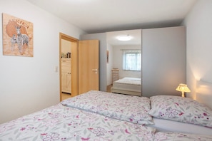 Une chambre à coucher comprenant un lit, une armoire, un miroir et une décoration murale représentant un zèbre.