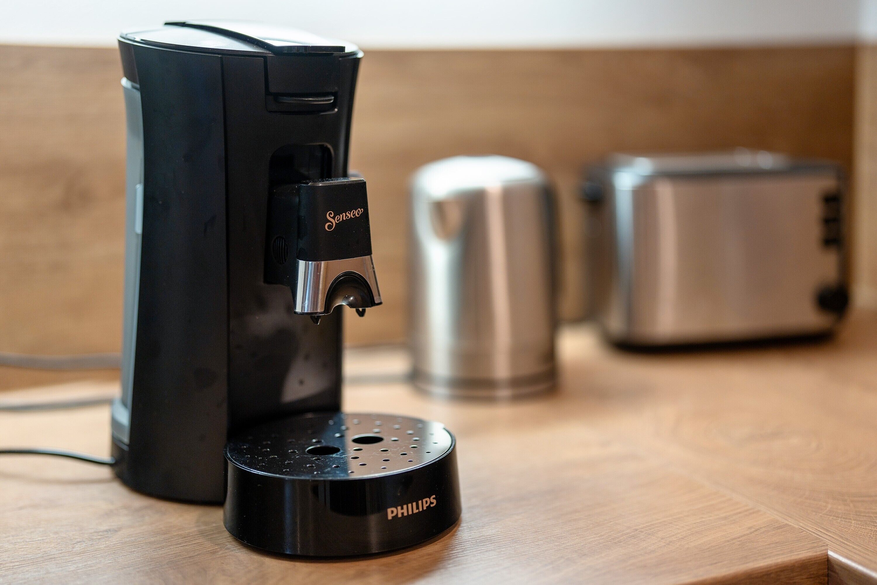 Kaffemaskine med vandbeholder og kaffekande på en træoverflade.