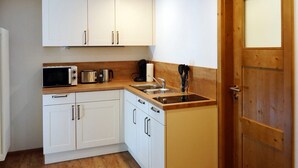 A compact kitchen with white cabinets, a microwave, toaster, and a sink. - Holiday Apartment Im Denkmal 1 with Wi-Fi (Alpirsbach)