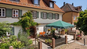 A traditional European-style building with a courtyard, outdoor seating, and a green umbrella. - Holiday Apartment Im Denkmal 1 with Wi-Fi (Alpirsbach)
