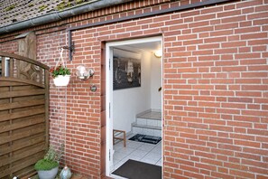 Ein Backsteinhaus mit einem Holztor, einem Blumentopf und einem gerahmten Bild an der Wand.