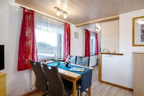 Un coin repas avec une table en bois, des chaises et des rideaux rouges.