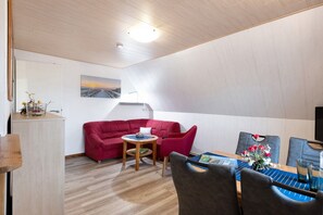 Une pièce moderne avec un canapé rouge, une petite table ronde et une table à manger avec des chaises.