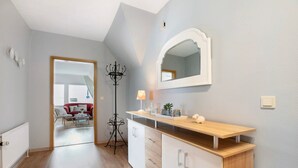 Ein modernes Interieur mit einer Holztresen, weißen Schränken, einem Spiegel und einem roten Sofa im Hintergrund.