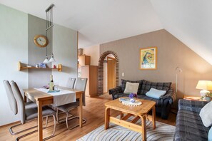 Ett mysigt vardagsrum med en matplats, ett träbord och en soffa.