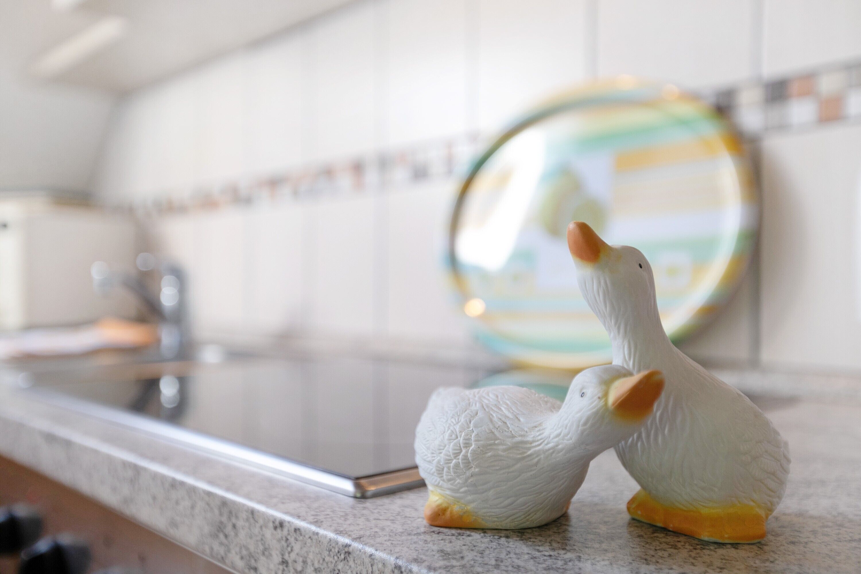 Two white ceramic ducks on a kitchen counter.
