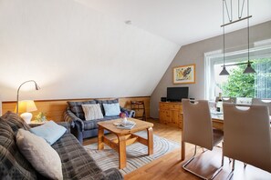Ett modernt vardagsrum med en soffa, ett soffbord och en matplats.