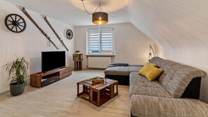A loft-style living room with a television, wooden coffee table, and a sofa with a yellow pillow. - Apartment 'Ferienwohnung Schwarzwaldliebe' with Private Terrace and Wi-Fi (Bad Peterstal-Griesbach)