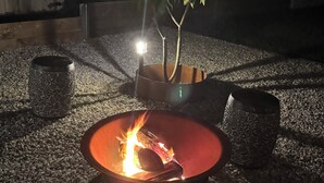 A fire pit with a fire burning, surrounded by decorative planters and a metal lantern. - Seaside escape awaits your family in Myalup! (Myalup)