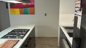 A modern kitchen with a gas stove, stainless steel appliances, and a colorful abstract painting on the wall. - Seaside escape awaits your family in Myalup! (Myalup)