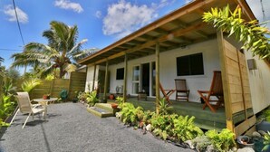 A single-story house with a covered porch, outdoor seating, and a garden with tropical plants. - ShineAwayHomes- Mountain view (Matavera District)