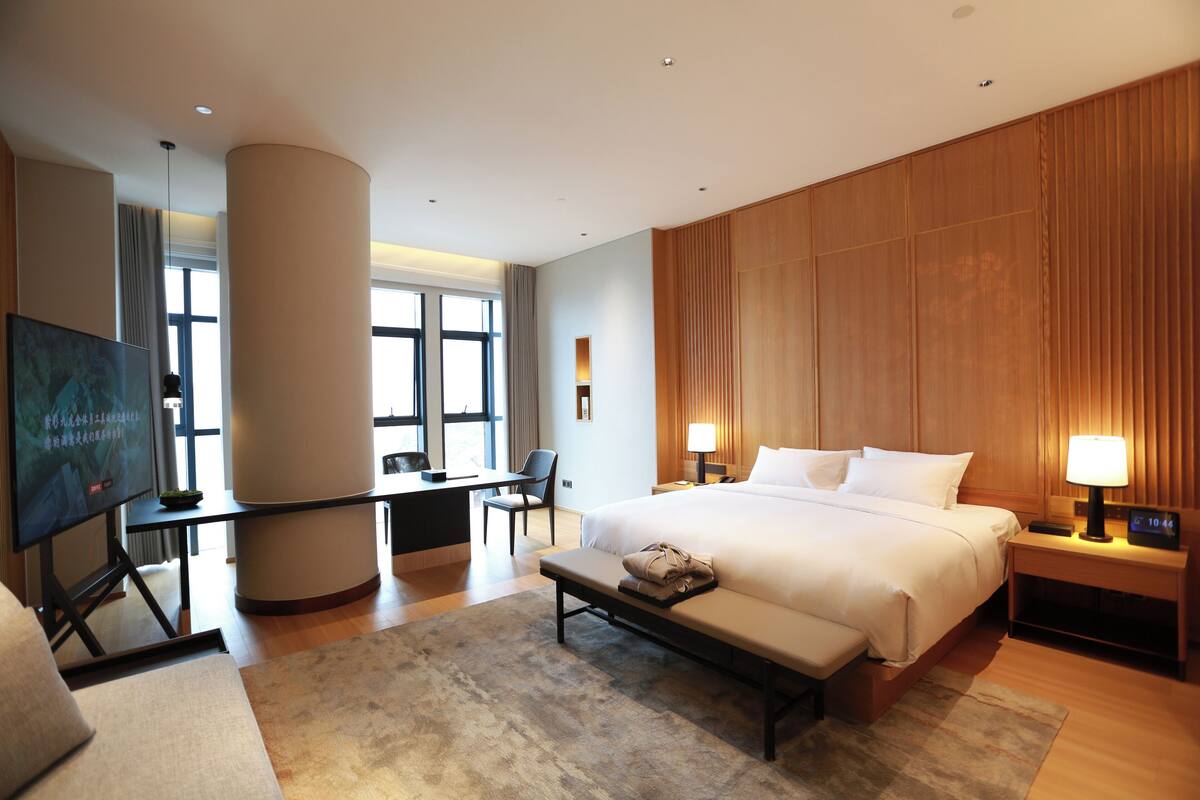 Una habitación de hotel moderna con una cama grande, mesitas de noche, un escritorio y un televisor.