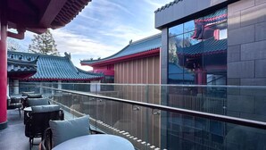A balcony with tables and chairs, overlooking traditional architecture.