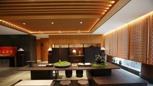 A modern interior with a wooden reception desk, seating area, and decorative elements.
