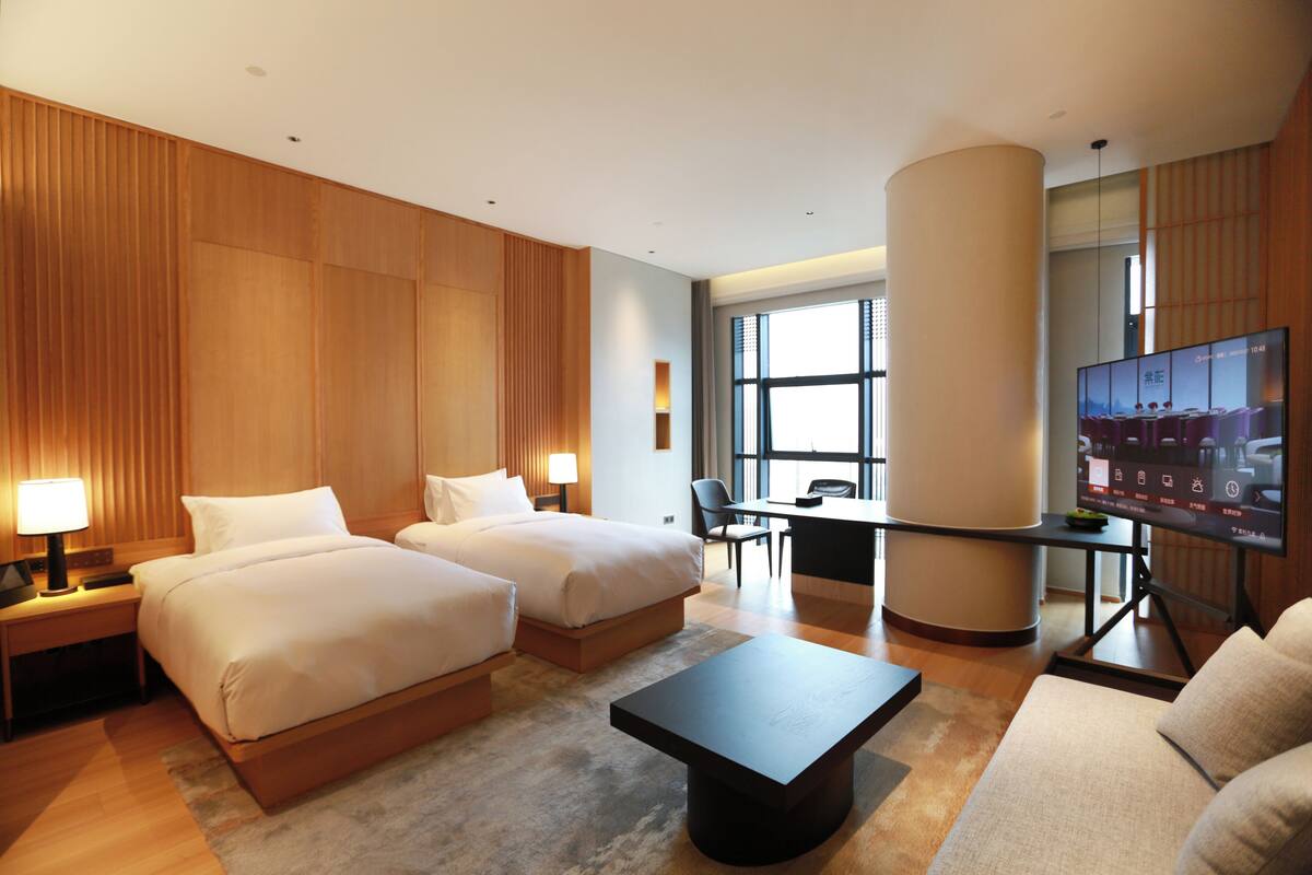 Habitación de hotel con dos camas, un escritorio, un televisor y un sofá.