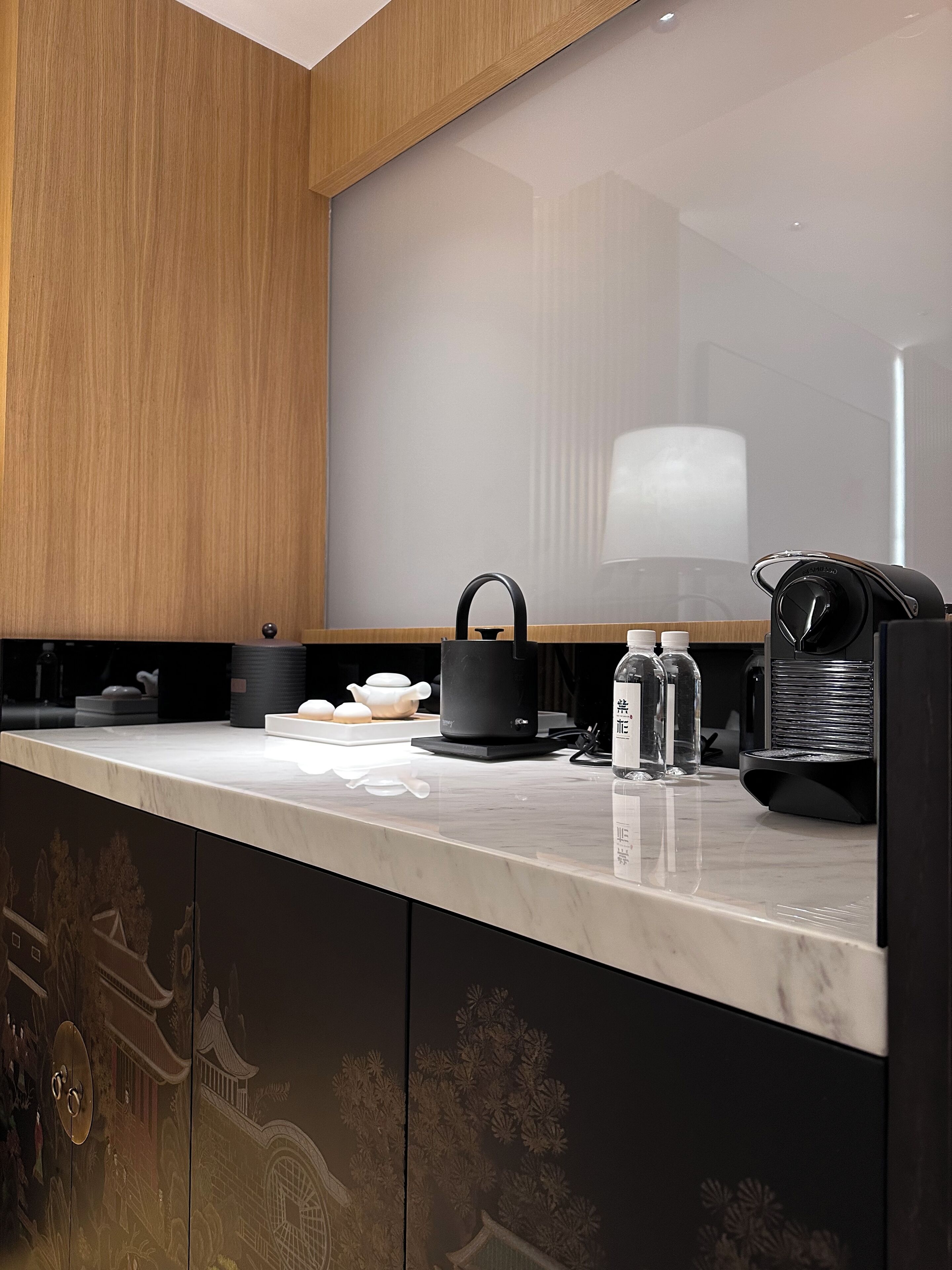 A modern kitchen with a marble countertop, a black kettle, a coffee machine, and a water dispenser.