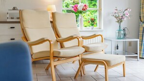 Una habitación con dos sillones color beige, una mesita con lámpara y una ventana con vistas a zonas verdes.