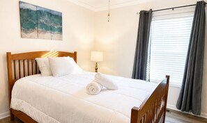 A neatly made bed with white bedding and a rolled towel, a bedside lamp, and a painting of a wave on the wall. - Beautiful, Cozy home in Concord providing a spacious & tranquil retreat (Concord)