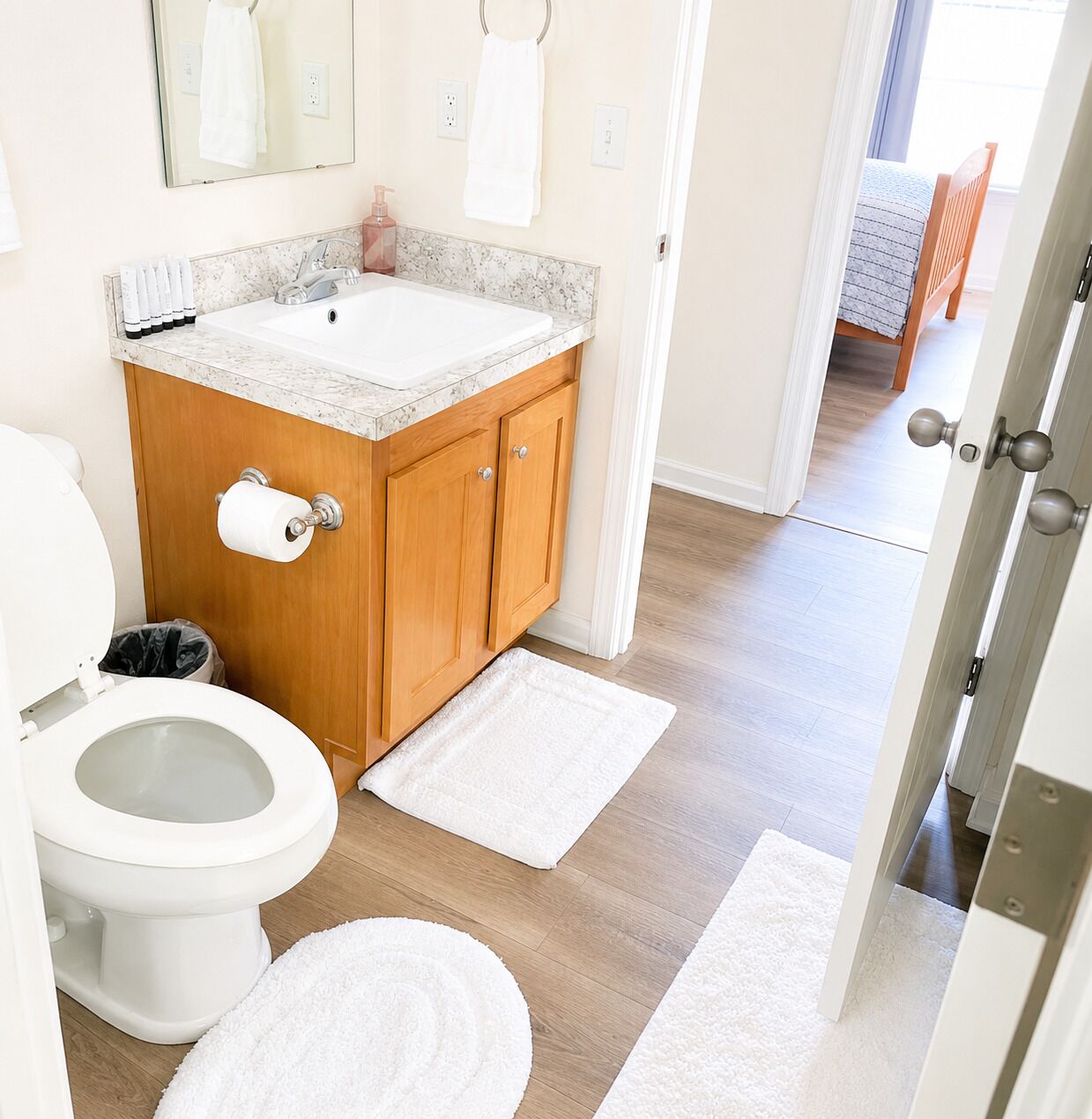 A bathroom with a toilet, sink, and wooden cabinets.
