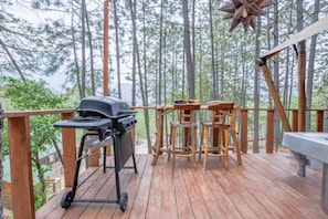 Un patio in legno con un barbecue, un tavolo e sedie.