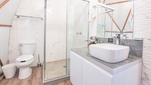 Ein modernes Badezimmer mit Duschkabine aus Glas, einer weißen Toilette und einem Marmorwaschtisch.