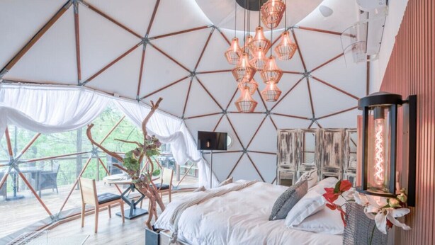 Ein geräumiges Zimmer mit einem großen Bett, einer Essecke und Blick ins Freie.