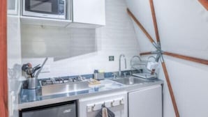 Une cuisine avec des meubles blancs, un four à micro-ondes, un évier et une cuisinière.