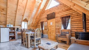 A log cabin with a dining area, kitchen, and a fireplace.