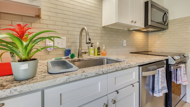 A modern kitchen with white cabinetry, a granite countertop, stainless steel appliances, and a potted plant. - Peaceful Fairhope Getaway, 2 Mi to South Beach (Fairhope)