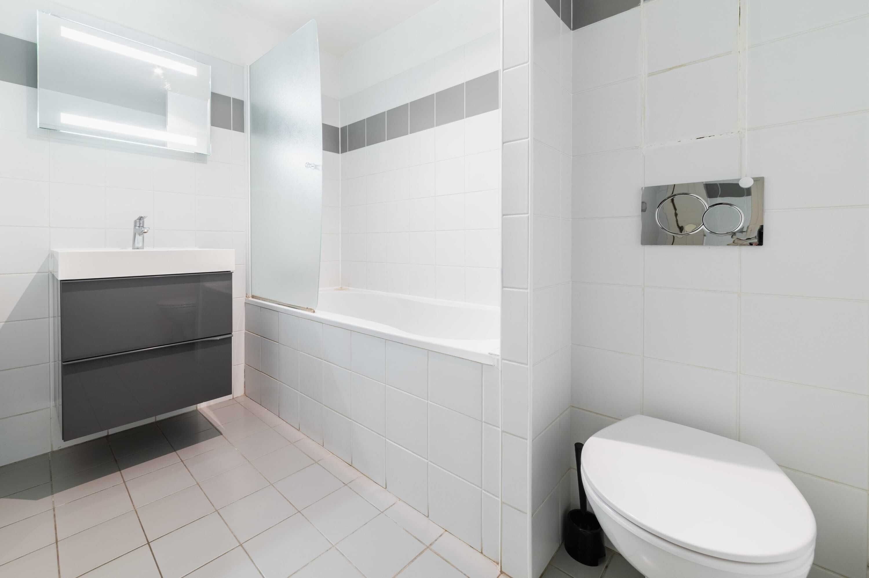 Une salle de bain avec un lavabo blanc, un miroir, une baignoire et des toilettes.