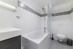 Un baño moderno con bañera, inodoro y cabina de ducha de vidrio.