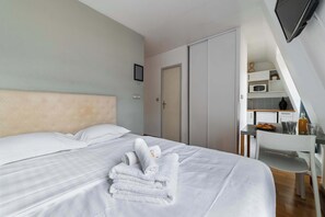 Una habitación de hotel con cama, escritorio y kitchenette.