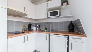 Une cuisine avec des meubles blancs, un four à micro-ondes, un évier et une machine à café.