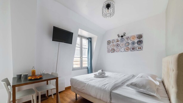 Une pièce comprenant un lit, un bureau, des chaises, un téléviseur et une fenêtre.