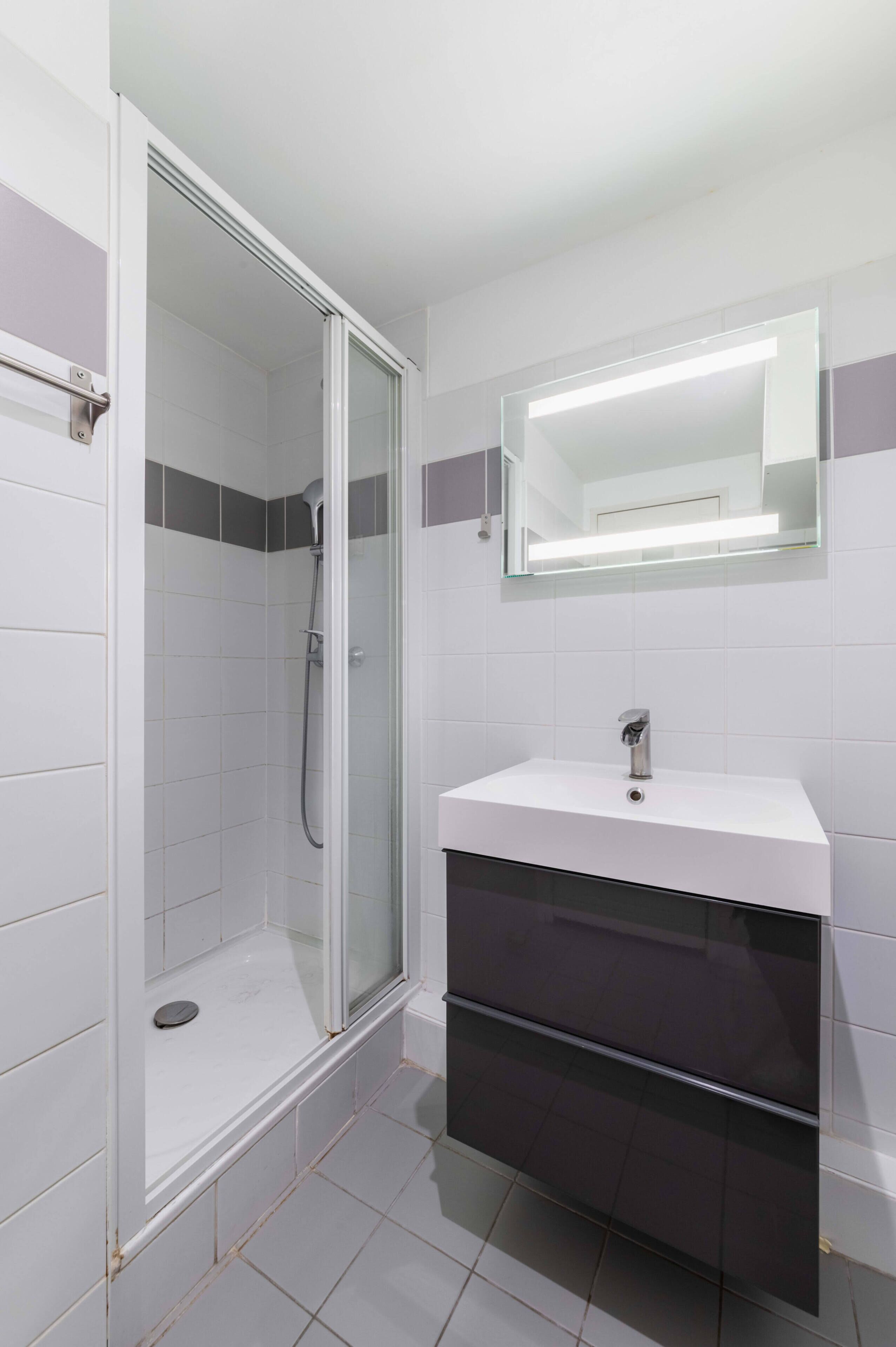 Une salle de bain avec une douche, un lavabo et un miroir.