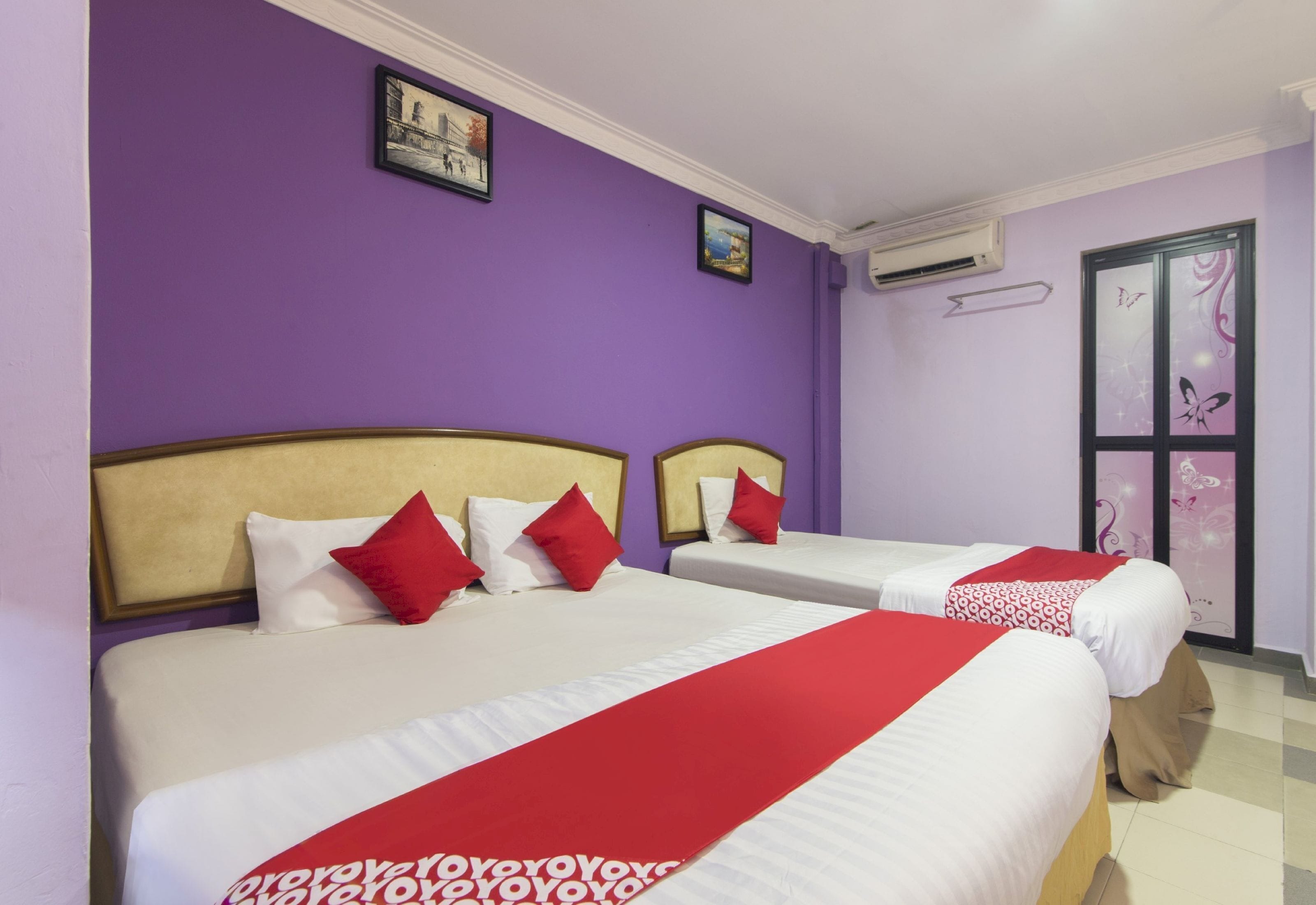 A hotel room with two beds, purple walls, and a window with butterfly decals.