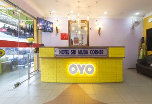 Un mostrador de recepción de hotel con un esquema de color amarillo brillante y un llamativo logo 'OYO'.