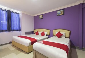 Habitación de hotel con dos camas, paredes moradas y una ventana con cortinas azules.