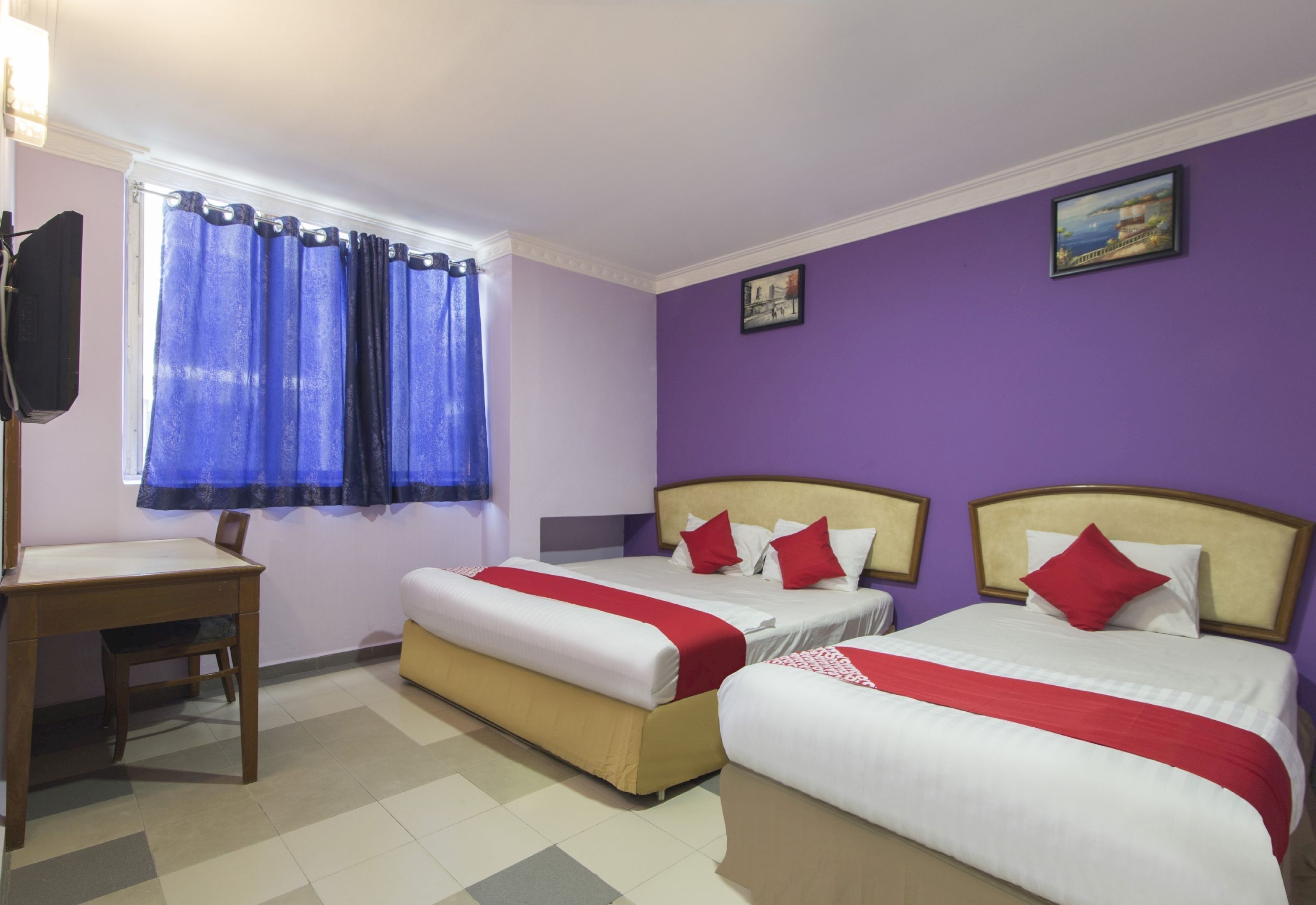 A hotel room with two beds, a desk, and a window with curtains.