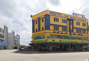 Un hotel de varios pisos con fachada amarilla y azul, un restaurante llamado M. Tasleem en la planta baja, y un letrero que dice 'Vivo' en el edificio contiguo.