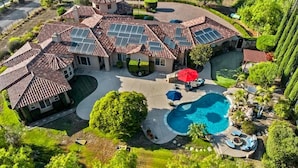 Una casa grande con piscina, paneles solares en el techo y un jardín bien cuidado.