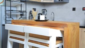 Een keuken met een houten aanrecht, witte stoelen en een metalen rek.