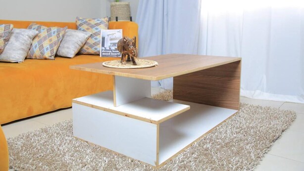 Een moderne woonkamer met een houten salontafel, een bank met gestreepte kussens, en een decoratief olifantje.
