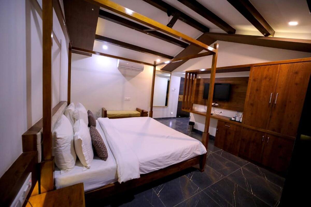 Un dormitorio con una cama con dosel, un armario de madera y una televisión.