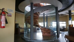 Un intérieur moderne avec un escalier en colimaçon en verre, un extincteur et un panneau indiquant qu’il est interdit d’apporter de la nourriture ou des boissons de l’extérieur.
