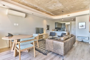 Una sala de estar moderna con una mesa de comedor, sofá y zona de cocina.